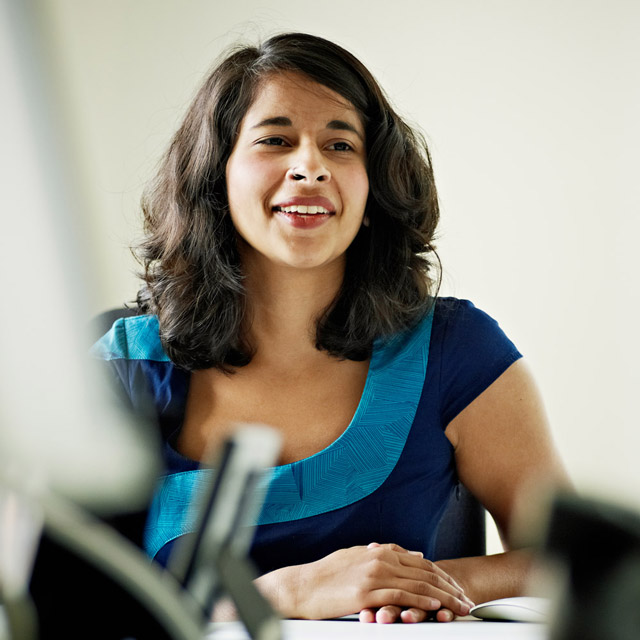 Businesswoman in discussion at workstation in office smiling
