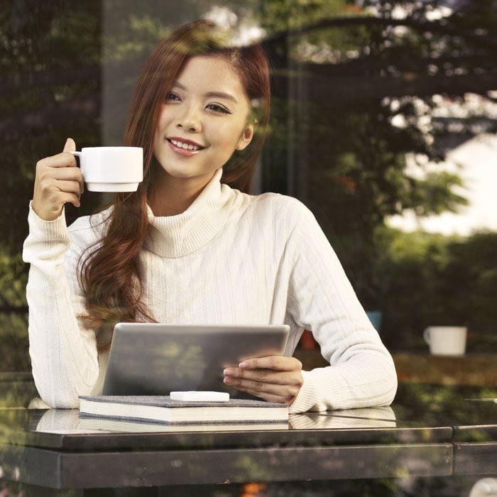 Mujer sonriente con una taza y tablet