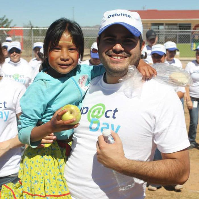 Voluntario de Deloitte sosteniendo una niña escolar