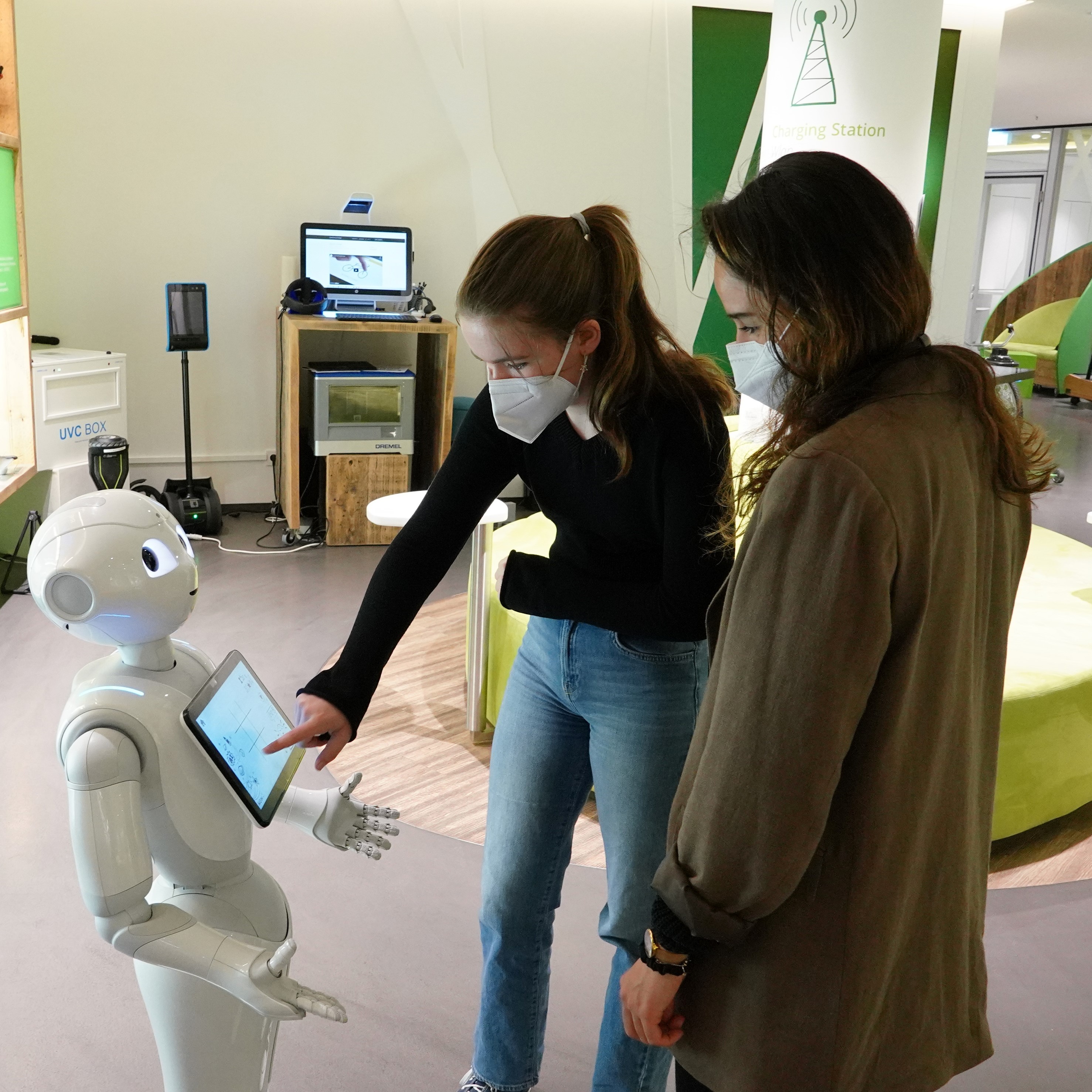 Zwei Schülerinnen beschäftigen sich mit dem Roboter "Pepper".