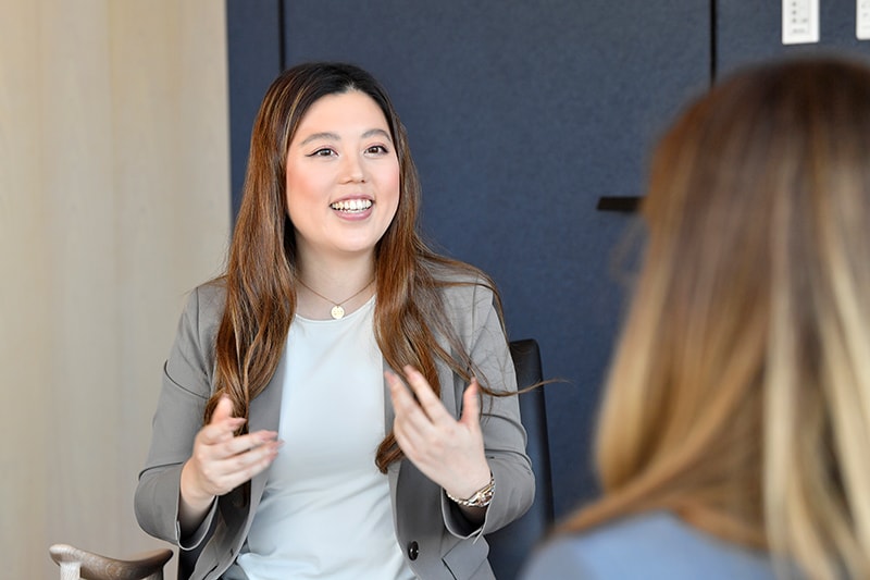 藤本 真里絵の写真。肩までの茶髪の日本人女性で、白いシャツとグレーのスーツを着ている。