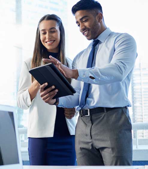 Young man and woman in office setting looking at tablet screen