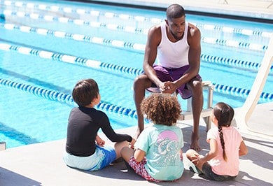 Jamal speaking with kids beside swimming pool